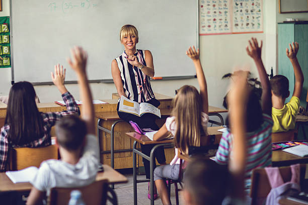 istock Smiling elementary school teacher asking the question in the classroom. 639439572