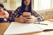 Close up of schoolgirl using mobile phone in the classroom.