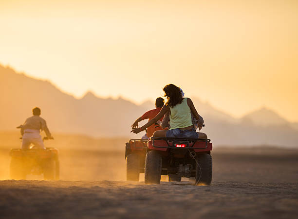 rear view of friends on quad bikes in the desert. - off road vehicle quadbike desert dirt road imagens e fotografias de stock