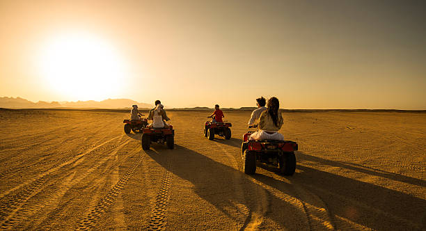 vue panoramique des personnes conduisant des quads dans le désert. - off road vehicle quadbike desert dirt road photos et images de collection