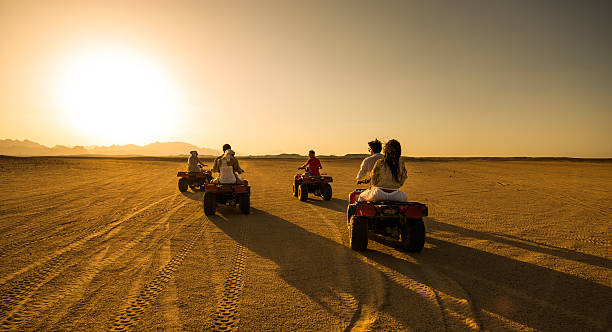 vista panoramica delle persone che guidano quad nel deserto. - off road vehicle quadbike desert dirt road foto e immagini stock