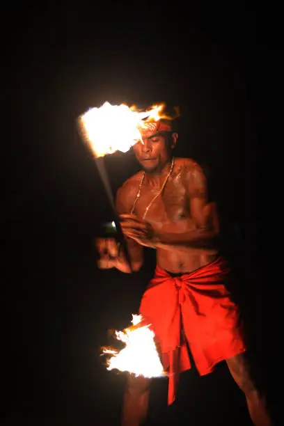 Indigenous Fijian holds a torch during a fire dance at nigh in Fiji. Real people copy space