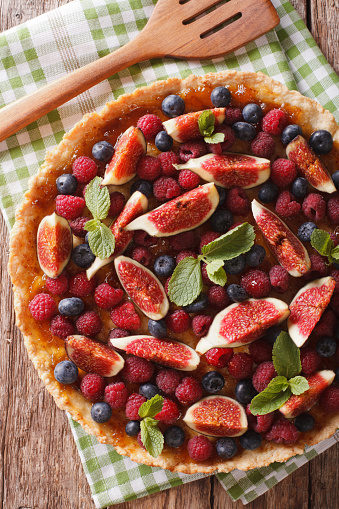 Delicious tart with fresh fruit and berries close up on the table. vertical view from above
