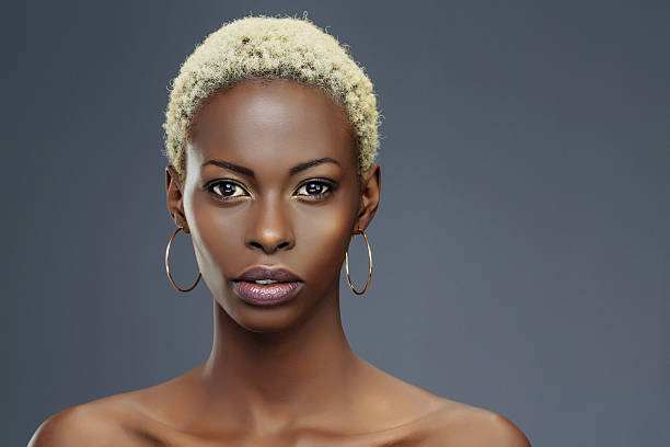 Beauty portrait  Fashion  Beautiful african ethnicity  young women Beauty, fashion portrait. Original looks. Beautiful, lovely  and sensual young african girl.  Attractive African ethnicity,  slim women,  blonde, short hair.  Gray wall background. blond hair fine art portrait portrait women stock pictures, royalty-free photos & images