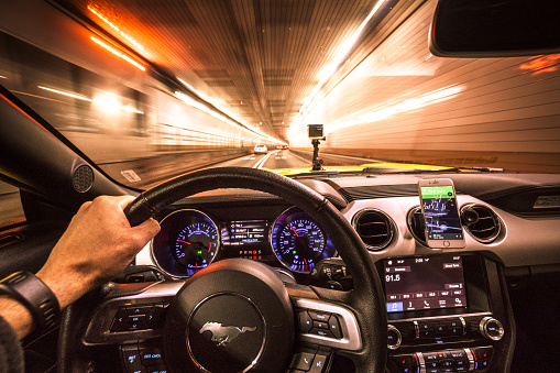 New York City, New York, USA - October 18, 2016: Interior view of a Ford Mustang car dashboard during the night on the traffic inside the new jersey tunnel in new york city.. The Mustang is an iconic american couple made by Ford in USA. The car is running fast in the street during the night.