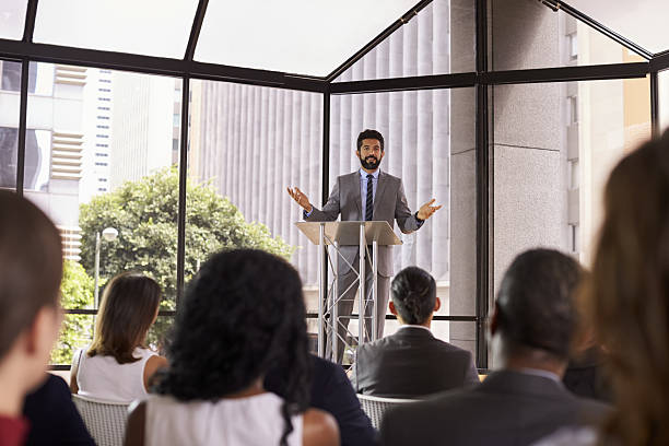 istock Hispanic man gesturing to audience at business seminar 639466598