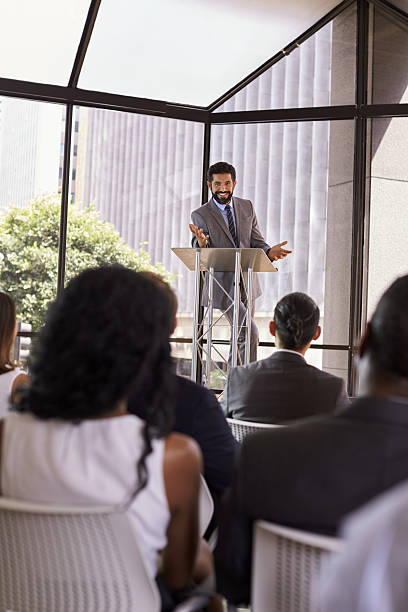 istock Hispanic man presents business seminar to audience, vertical 639466716