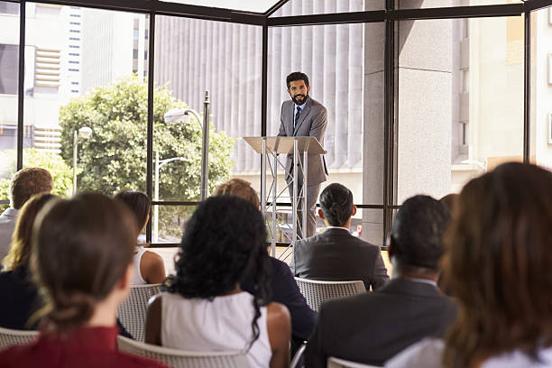 istock Hispanic man presenting business seminar leaning on lectern 639466718