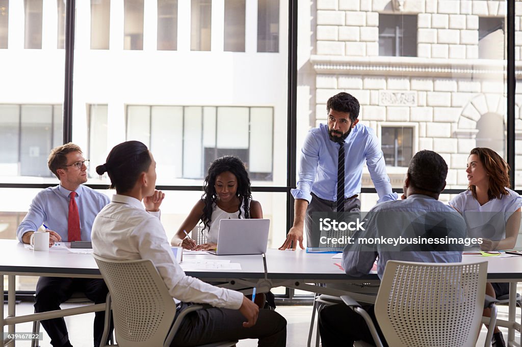 Manager standing to address colleagues at a business meeting Serious Stock Photo