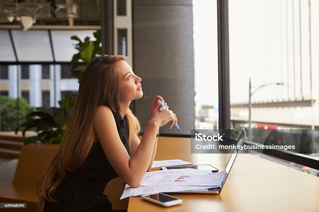 Businesswoman working in an office looking out of the window Contemplation Stock Photo