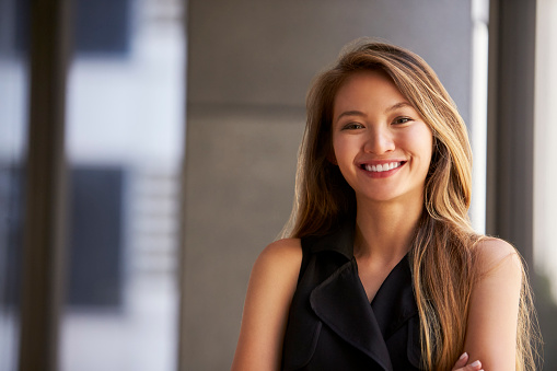 Joven empresaria asiática sonriendo a la cámara, de cerca photo