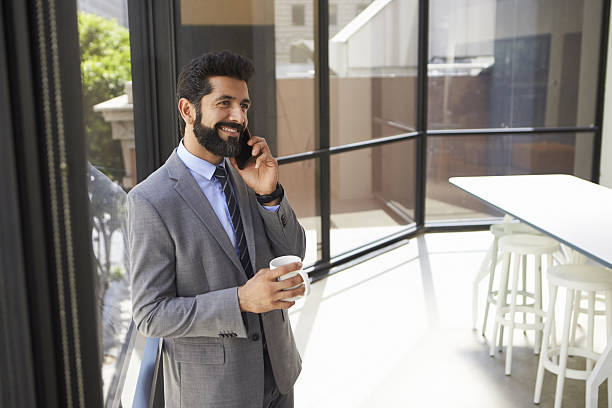 istock Middle aged Hispanic businessman using phone and holding cup 639468358