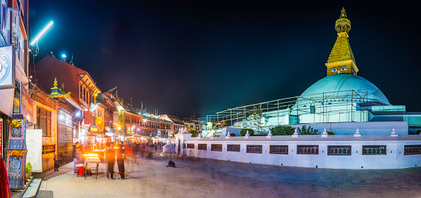 Kathmandu, Nepal - November 9, 2016: The iconic mandala dome of Boudhanath stupa, illuminated by spotlights as crowds of pilgrims and tourists walk around the ancient Buddhist shrine, a UNESCO World Heritage Site in Kathmandu, Nepal's vibrant capital city. Composite panoramic image created from eight contemporaneous sequential photographs.