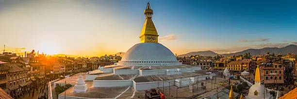 The iconic mandala dome of Boudhanath stupa, illuminated by warm sunset light as crowds of pilgrims and tourists walk around the ancient Buddhist shrine, a UNESCO World Heritage Site in Kathmandu, Nepal's vibrant capital city.