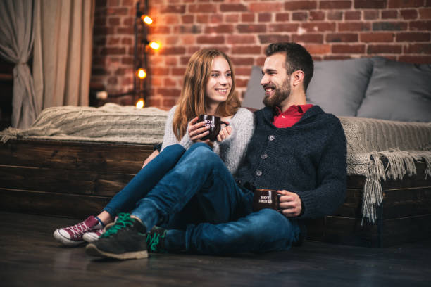 молодая пара на дому - brick red wool heat стоковые фото и изображения