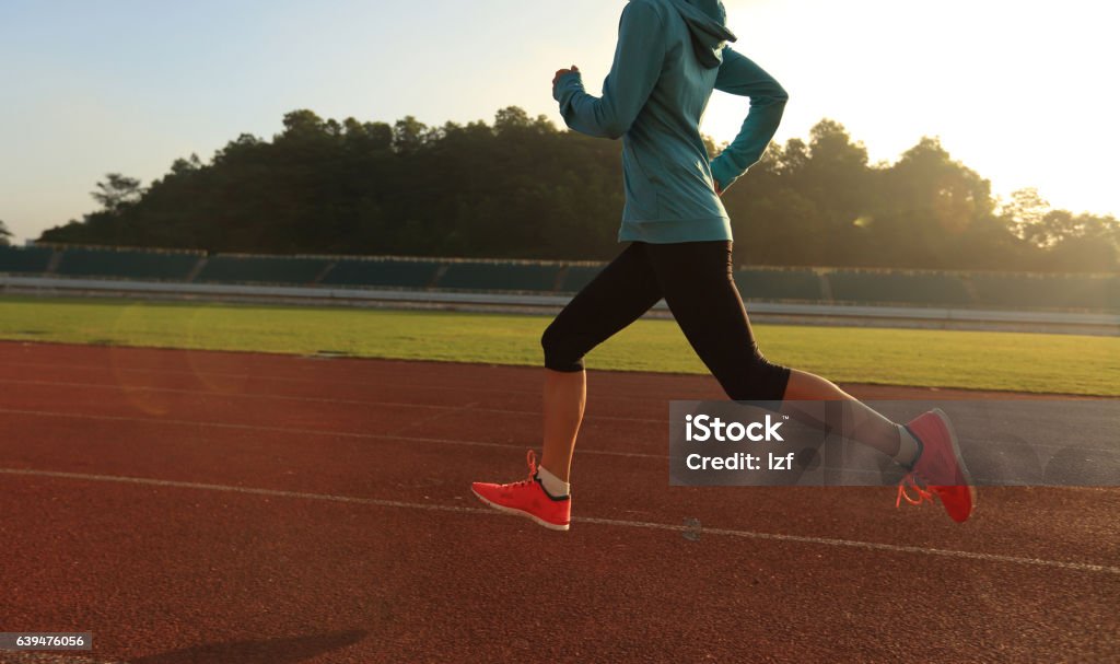 Young woman running during sunny morning on stadium track 20-29 Years Stock Photo