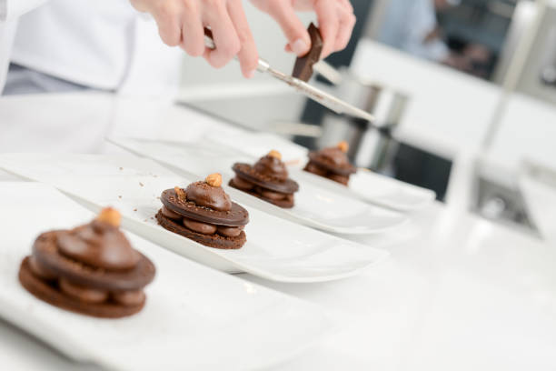 close up of professional pastry cook hands preparing chocolate dessert in restaurant kitchen