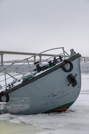Sunken ship in a frozen river covered with ice