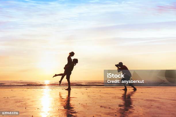 Photo libre de droit de Photographe De Mariage Travaillant Avec Un Couple Sur La Plage banque d'images et plus d'images libres de droit de Photographe