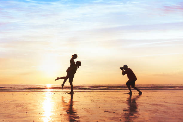 fotograf ślubny pracujący z parą na plaży - professional photographer zdjęcia i obrazy z banku zdjęć