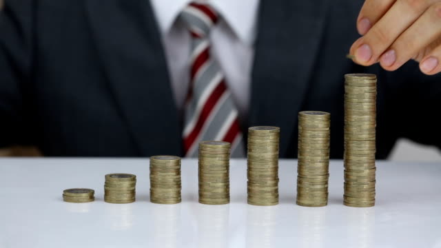 Businessman Protecting And Rising Coins Stack On Desk