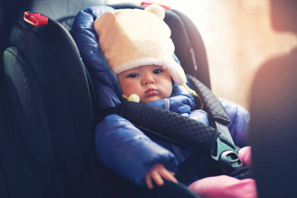очаровательная маленькая девочка, сидящая в машине в зимней одежде - car baby baby car seat child стоковые фото и изображения