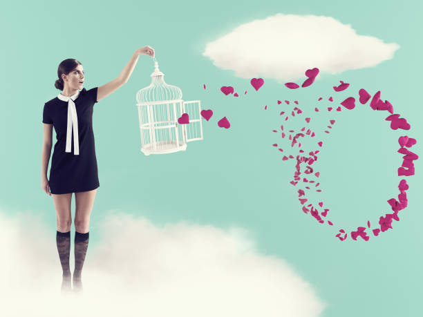 케이지가 날아다니는 마음을 사로잡으며 구름 위에 서 있는 여자. 발렌타인 데이 - women sign love trap 뉴스 사진 이미지