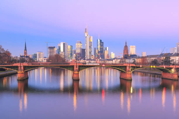 Picturesque view of Frankfurt am Main skyline and Ignatz Bubis Brucke bridge at sunrise with mirror reflections in the river, Germany