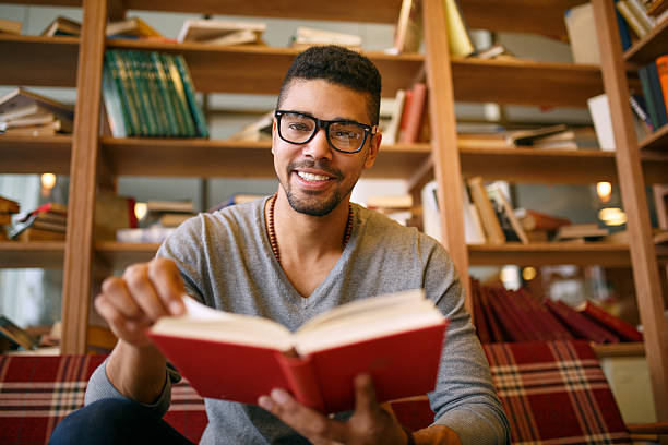 istock Smiling African American student  enjoying book reading in library. 639492866