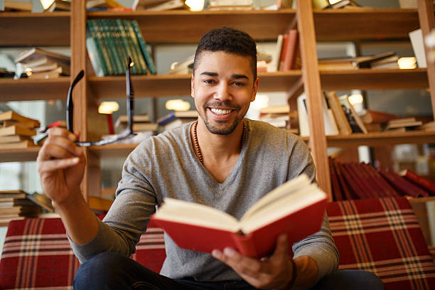 istock Smiling African American student enjoying book reading in library. 639492954