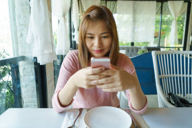 istock Asian woman using smart phone in restaurant 639494238