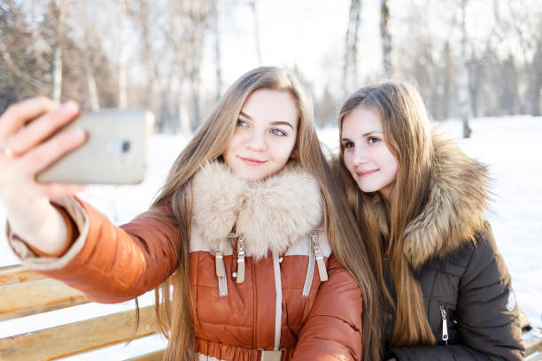 istock Two smiling girls make selfie in winter park 639496732