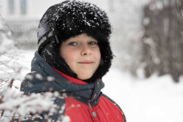 istock Smiling boy in a winter cap near  snow-covered bush 639499940