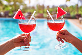 couple drinking cocktails near luxurious swimming pool in hotel