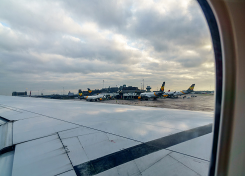 Manchester, UK - December 30, 2016: View of stationary aircraft at their gates at Manchester Airport through the window of a departing plane