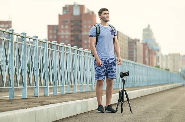 man with camera on tripod - reportage photographer photographing street imagens e fotografias de stock