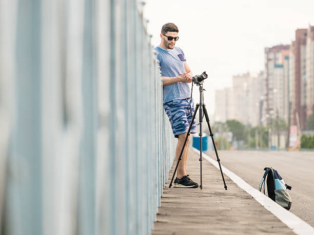 man with camera on tripod - reportage photographer photographing street imagens e fotografias de stock