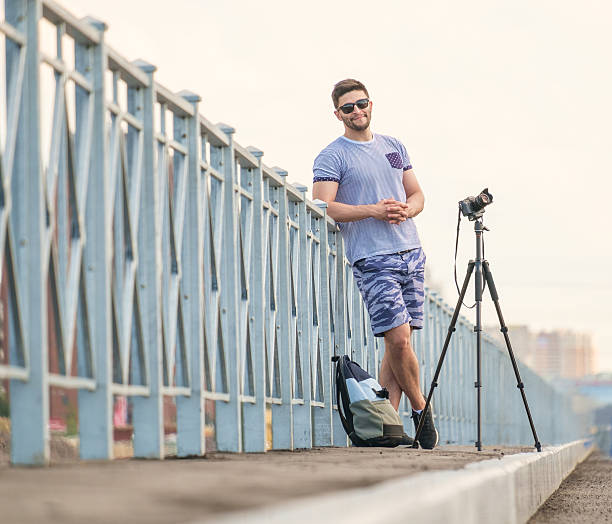 man with camera on tripod - reportage photographer photographing street imagens e fotografias de stock