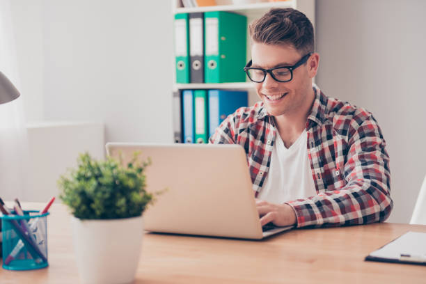 istock Handsome cheerful young man in glasses typing on laptop 639514102