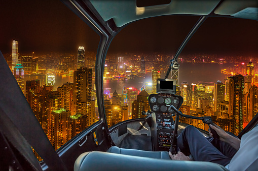 Aerial view inside helicopter cockpit night flight on Hong Kong cityscape in the night in Wan Chai district, Hong Kong island. Concept of transport, travel and business.