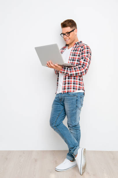 istock young blogger walking on laptop against white wall 639515704