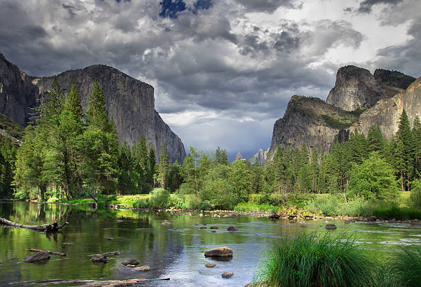 The granite formations of El Capitan and the Three Brothers, seen from the floor of Yosemite Valley across the Merced River, with a dramatic, overcast sky. Still taken from time lapse video #610816938