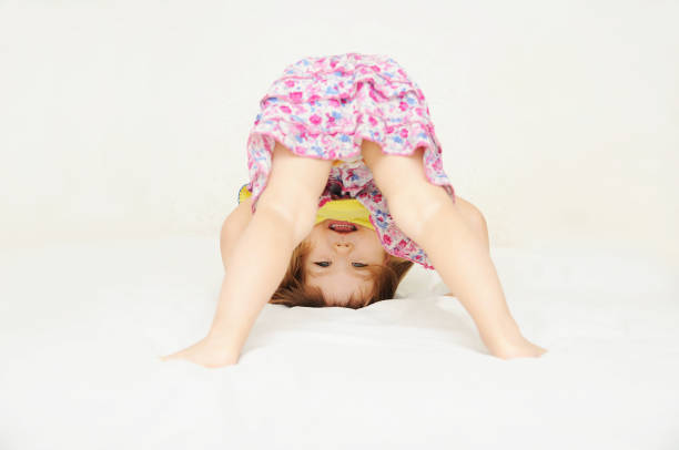 istock Smiling little girl standing on head upside down 639516508