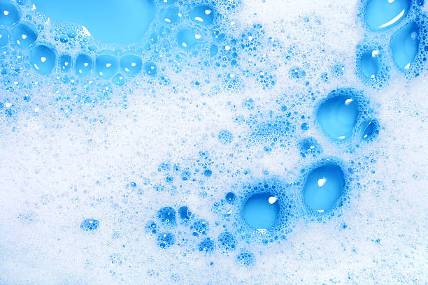 Soap sud close-up (blue) Close-up of soap sud with water on a blue background. soap sud foam bubble laundry stock pictures, royalty-free photos & images