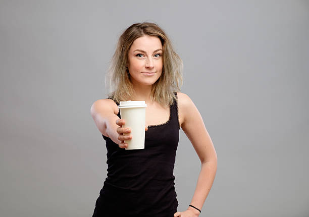 Young woman giving hot coffee to camera