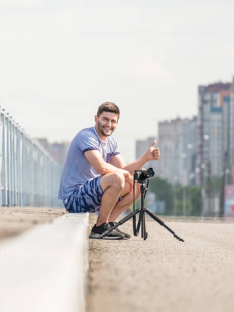 man with camera on tripod - reportage photographer photographing street imagens e fotografias de stock