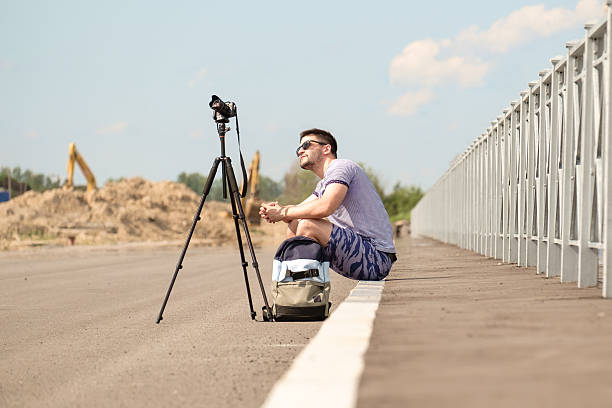 man with camera on tripod - reportage photographer photographing street imagens e fotografias de stock