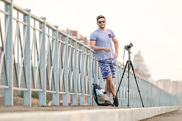 man with camera on tripod - reportage photographer photographing street imagens e fotografias de stock