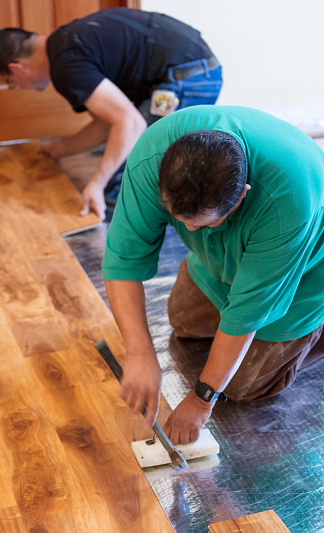 Men installing wood flooring in home.