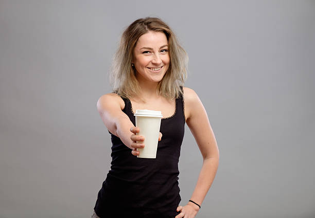 Young woman giving hot coffee to camera